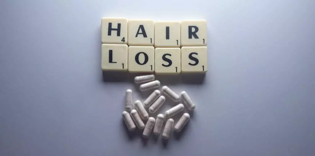 Hair loss text with white pills, hair fall and regrowth, Organic Biotin Supplements